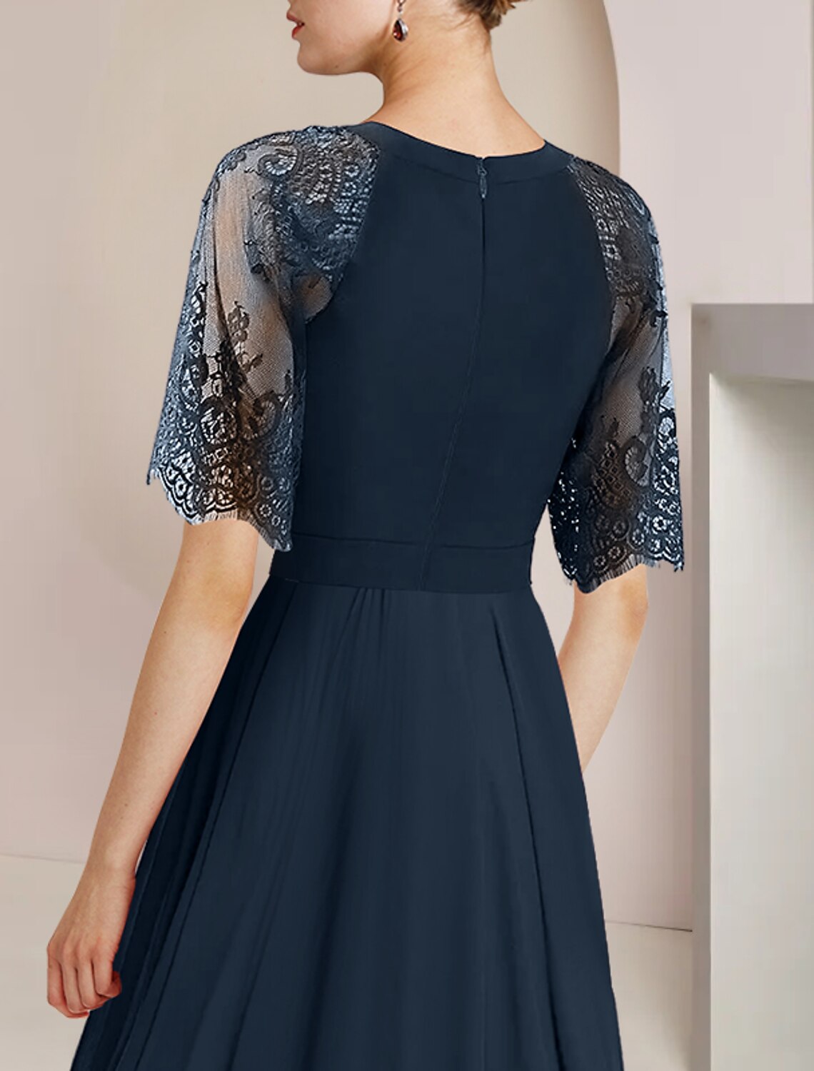 Close-up of the chiffon and lace fabric, pleats, and crystal brooch detail on the A-Line dress.
