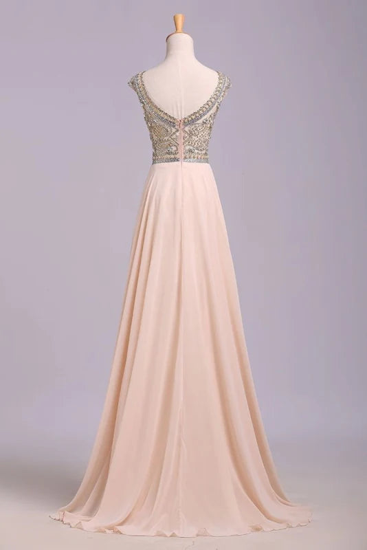 Back view of a model in a flowing chiffon A-line prom dress with intricate beading.