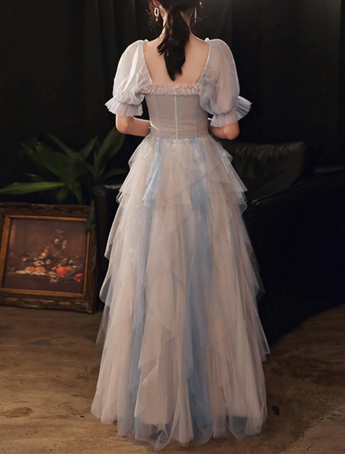 Model posing in a color block A-line prom dress with a flowing floor-length skirt.