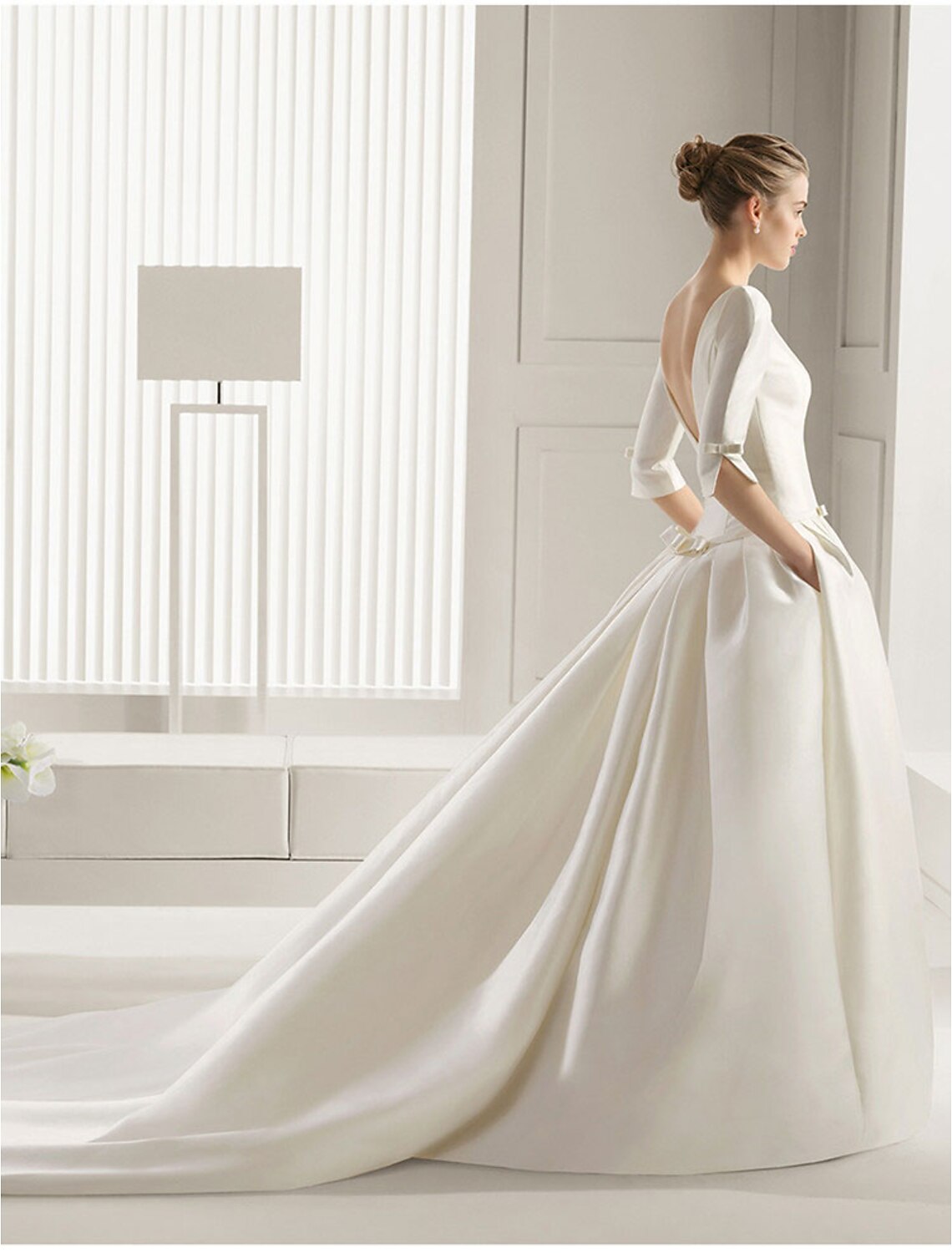 Back view of satin bridal gown showing court train and bow details.