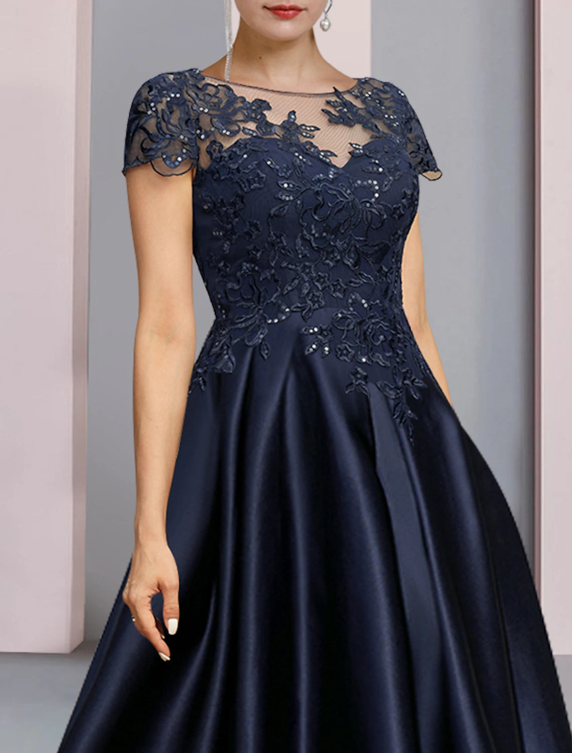 Close-up of sequin appliques on lace fabric of dress sleeve.
