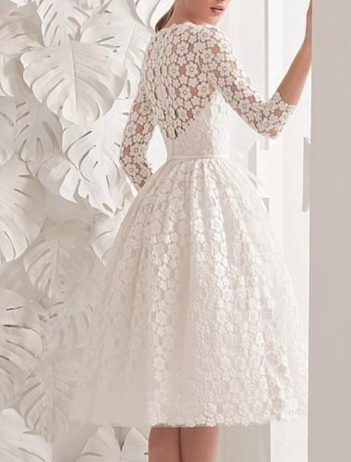 Back view of a white A-line dress showing lace appliques and ribbon details.