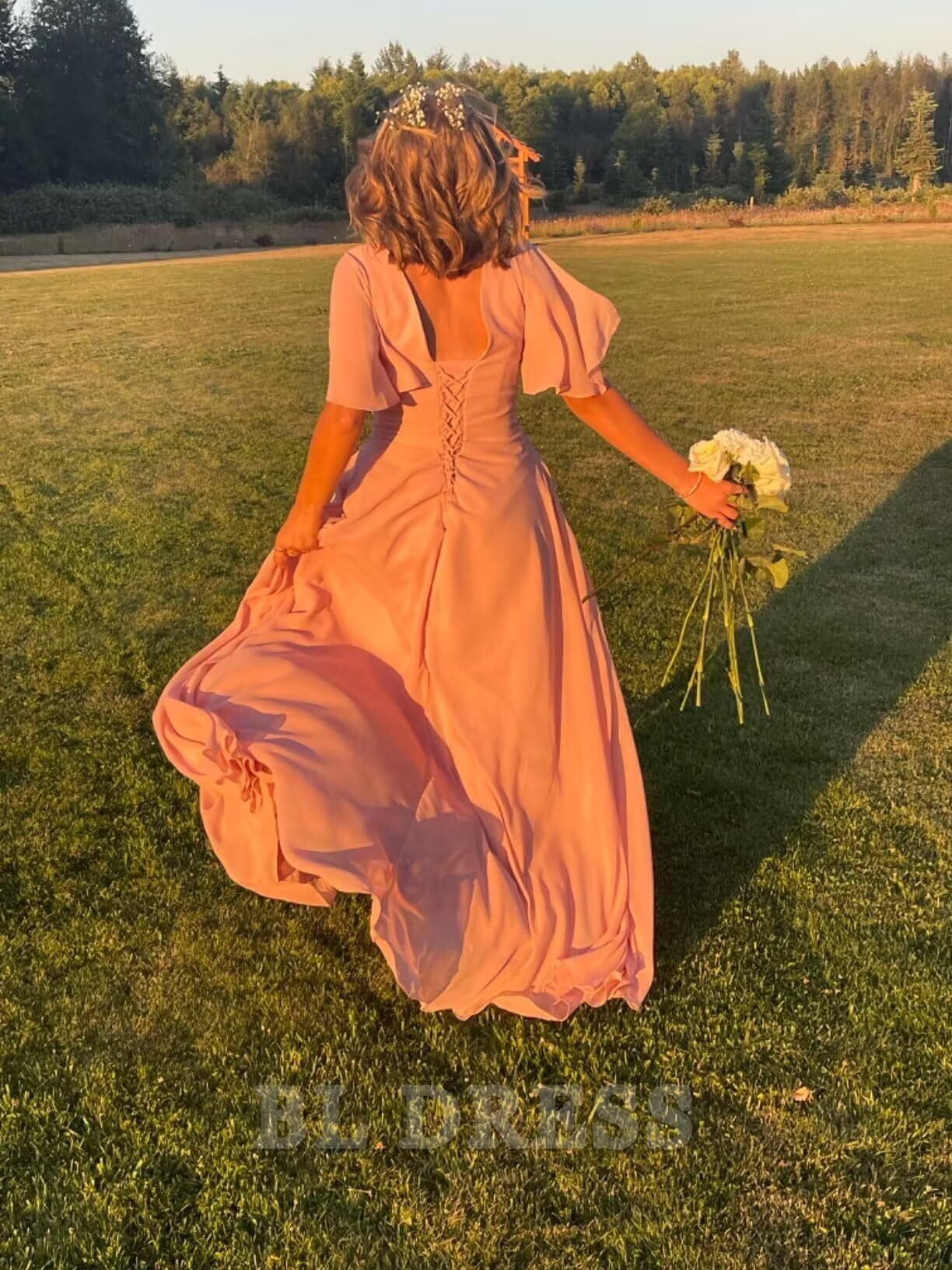 Back view of a woman in a flowing A-line chiffon formal dress.
