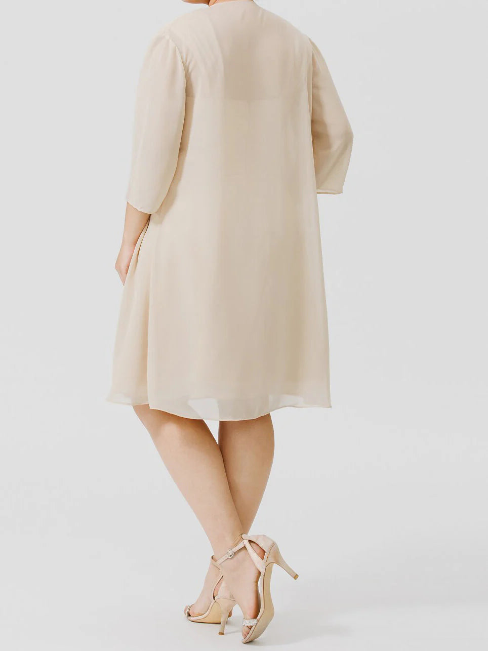 Woman posing in a formal knee-length A-line mother of the bride dress.