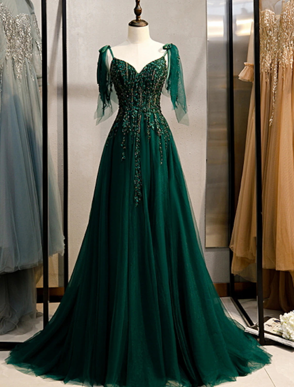 Elegant A-line formal dress with spaghetti straps, beading, and a sweep train on a model.