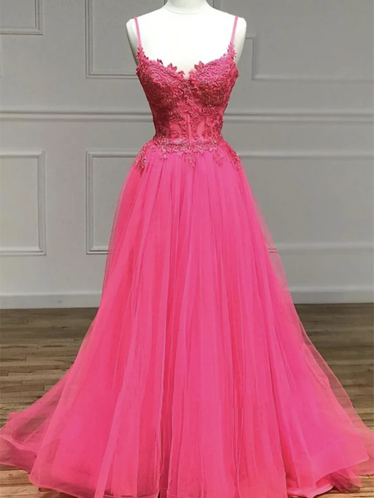 Woman wearing an elegant A-line spaghetti strap long prom dress with beaded lace details.