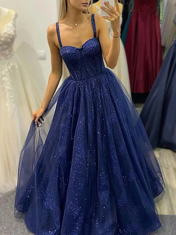 Woman wearing an elegant A-line spaghetti strap floor-length prom dress.