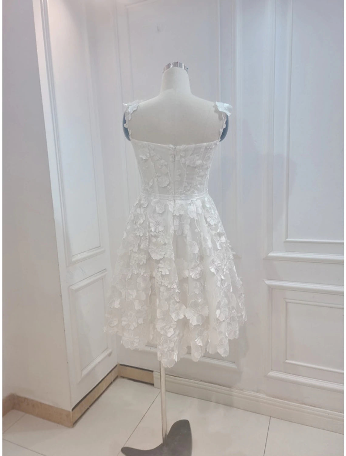 Back view of an A-line floral tulle cocktail dress with spaghetti straps.