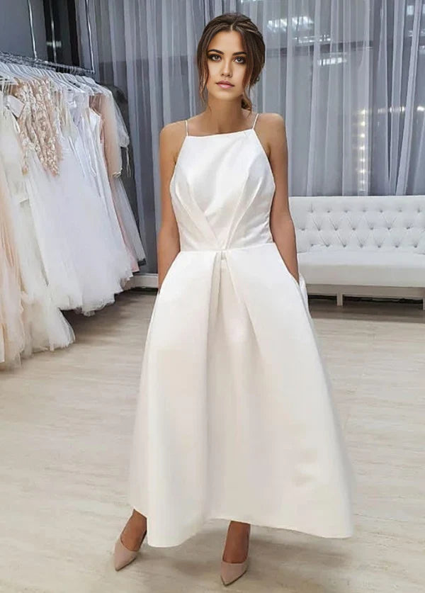 Front view of an A-Line tea length wedding dress with spaghetti straps and pockets.