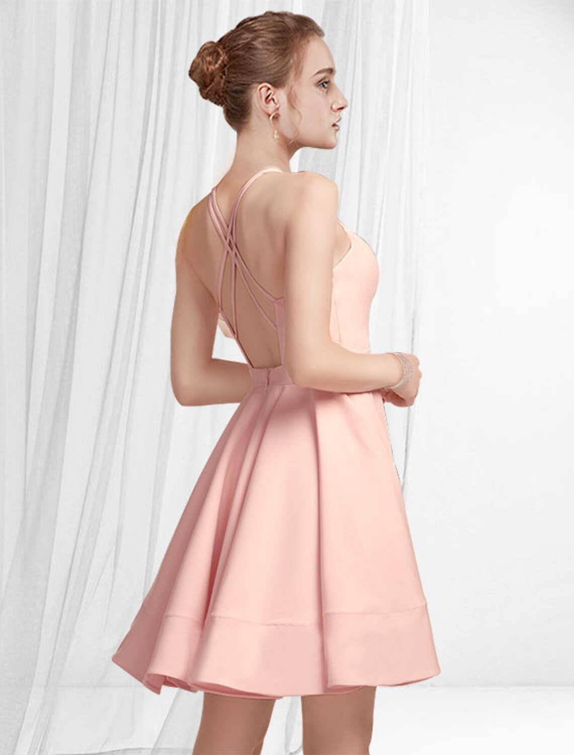 Back view of a pink A-line cocktail dress with a flowing pleated skirt.