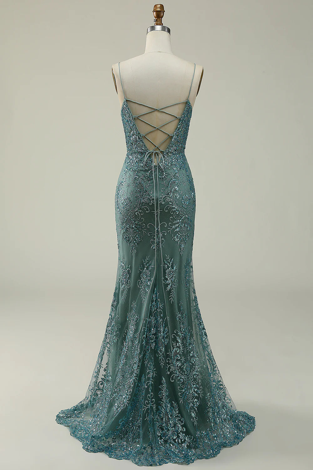 Side view of a model in a shimmering green sequin prom dress, showcasing the elegant slit.