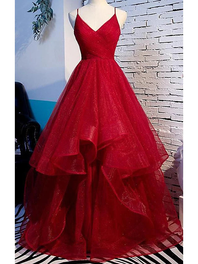 Woman wearing an elegant A-line spaghetti strap tulle prom dress with ruffles.