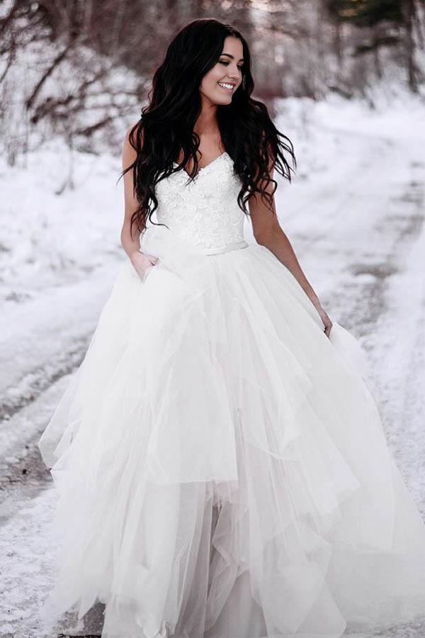 Elegant A-Line wedding dress with spaghetti straps, asymmetrical hem, and delicate lace details.
