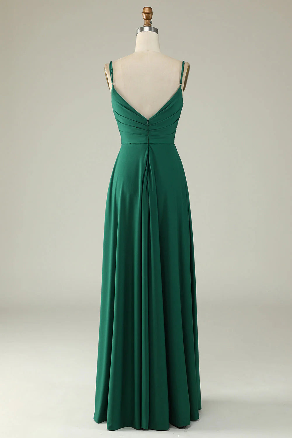 Model wearing an elegant dark green spaghetti strap long prom dress, side view.