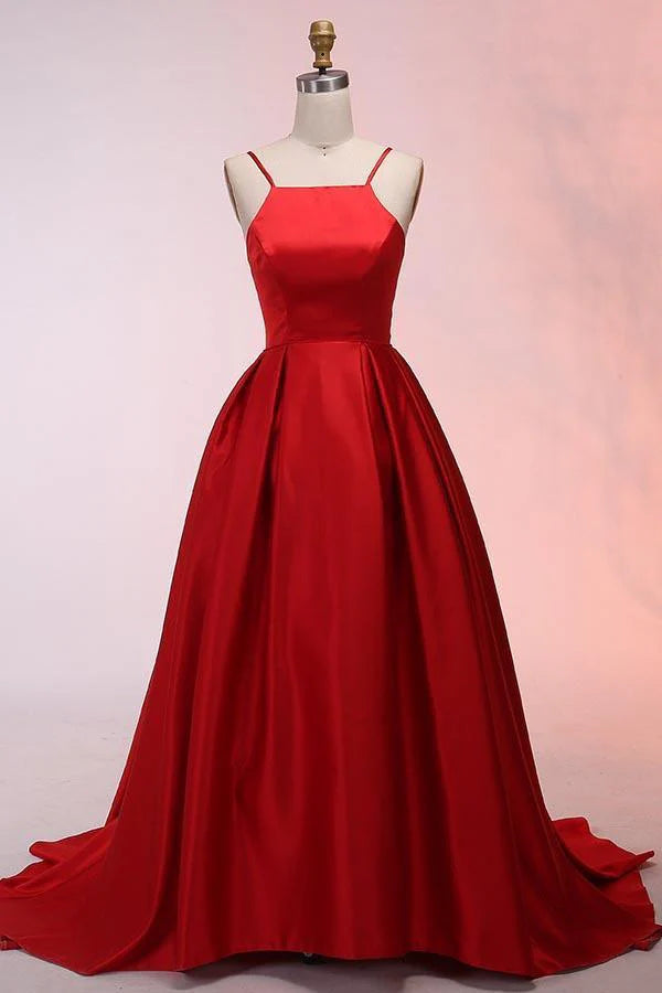 Woman wearing an elegant A-line satin prom dress with spaghetti straps and a sweep train.
