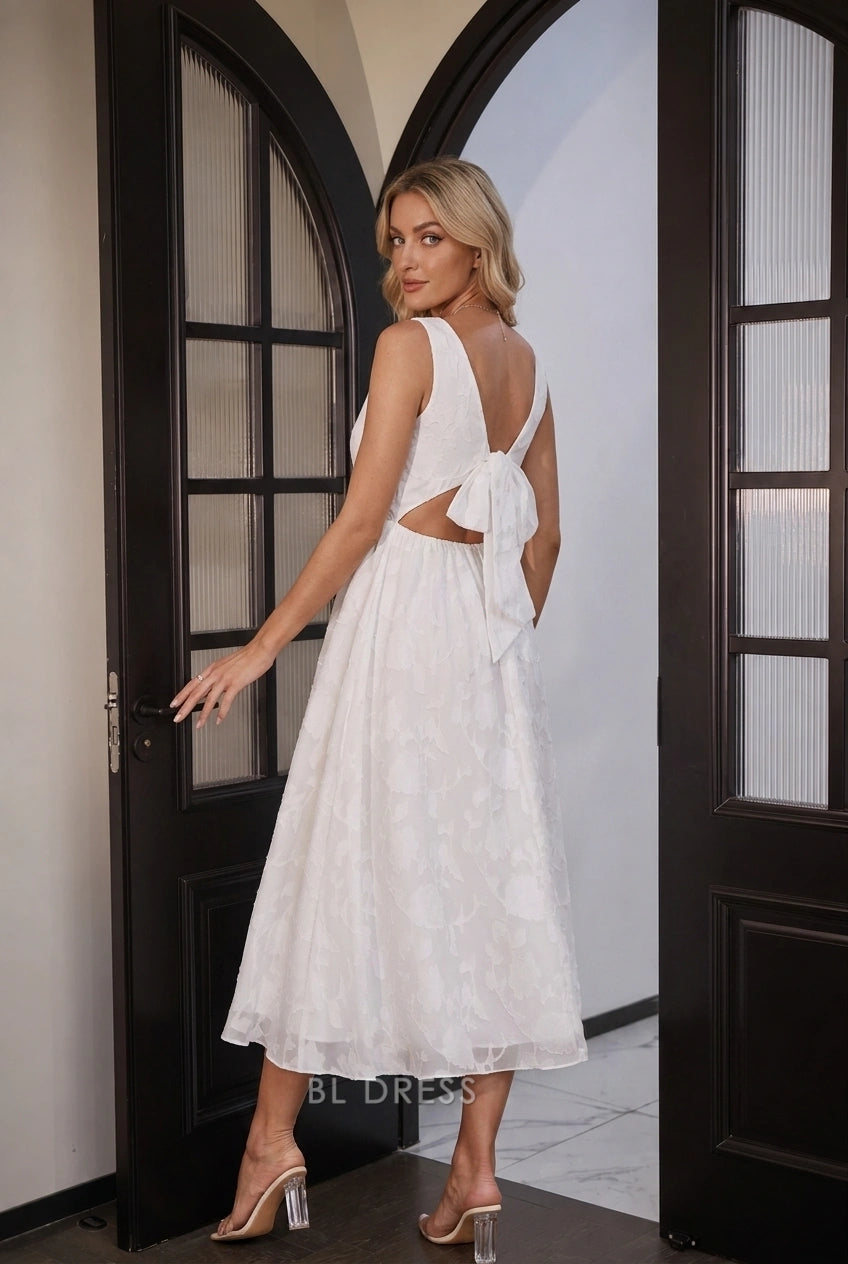 Close-up of the oversized bow on the open back of the white midi dress.