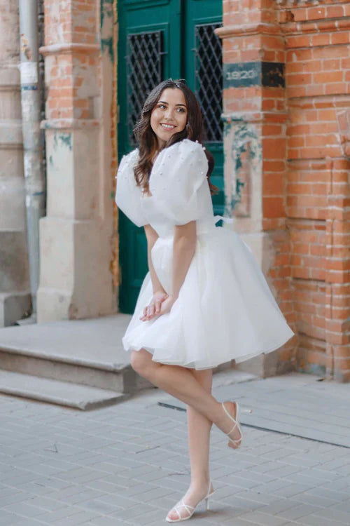Side view of an elegant short bridal dress featuring pearl details.