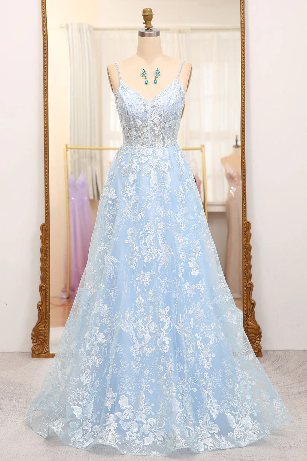 Model wearing a sky blue A-line tulle prom dress with a corset bodice and appliques.
