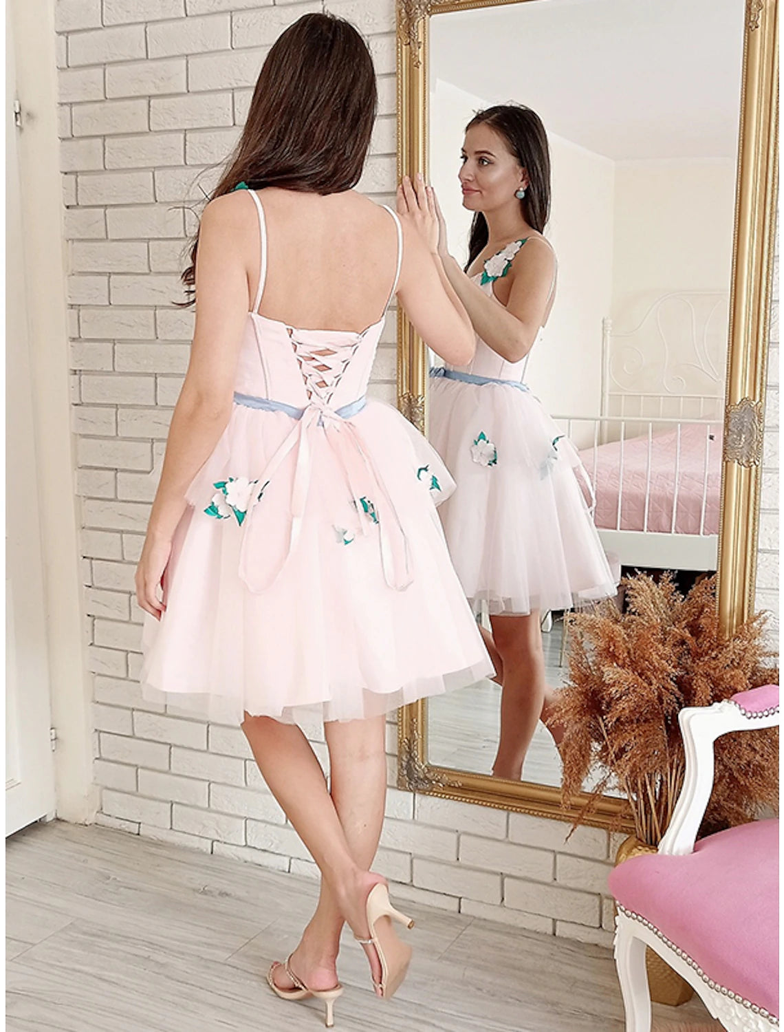 Side view of a woman wearing an A-line strapless floral lace mini dress.
