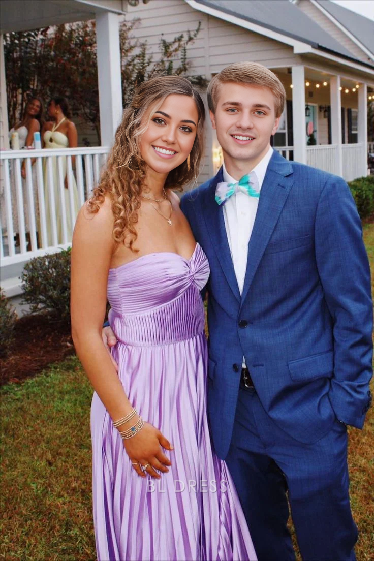 Woman wearing a light purple A-line strapless pleated long formal dress.