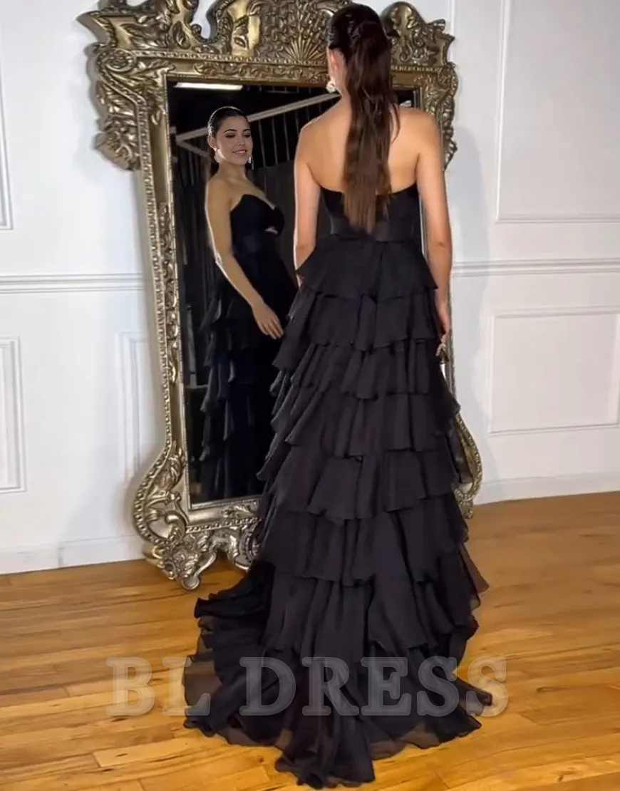 Back view of a black strapless A-line evening gown with flowing chiffon.