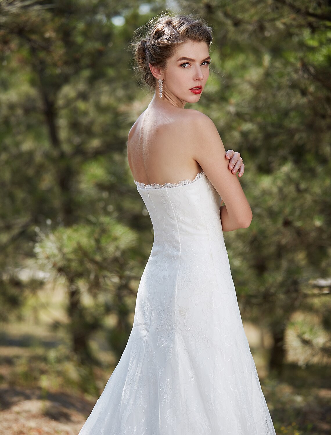 Side profile of a strapless satin wedding dress with a flowing court train.