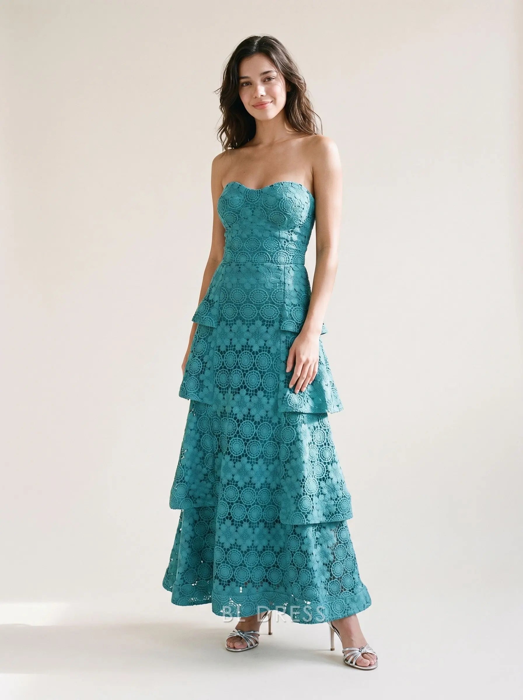 Woman in elegant teal strapless sweetheart neck tiered floral lace A-line prom dress.