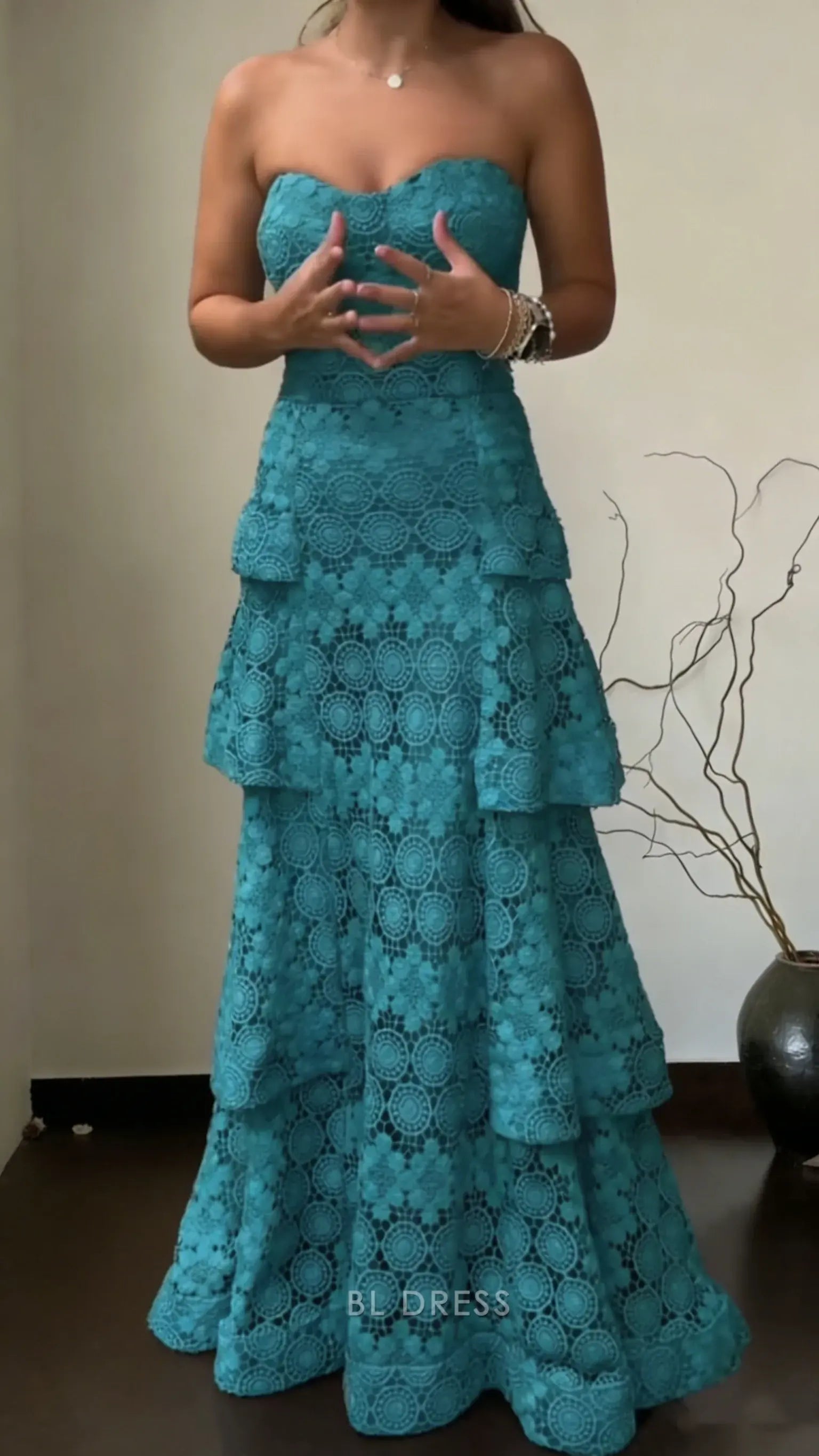 Side profile of woman wearing teal strapless A-line floral lace prom dress.