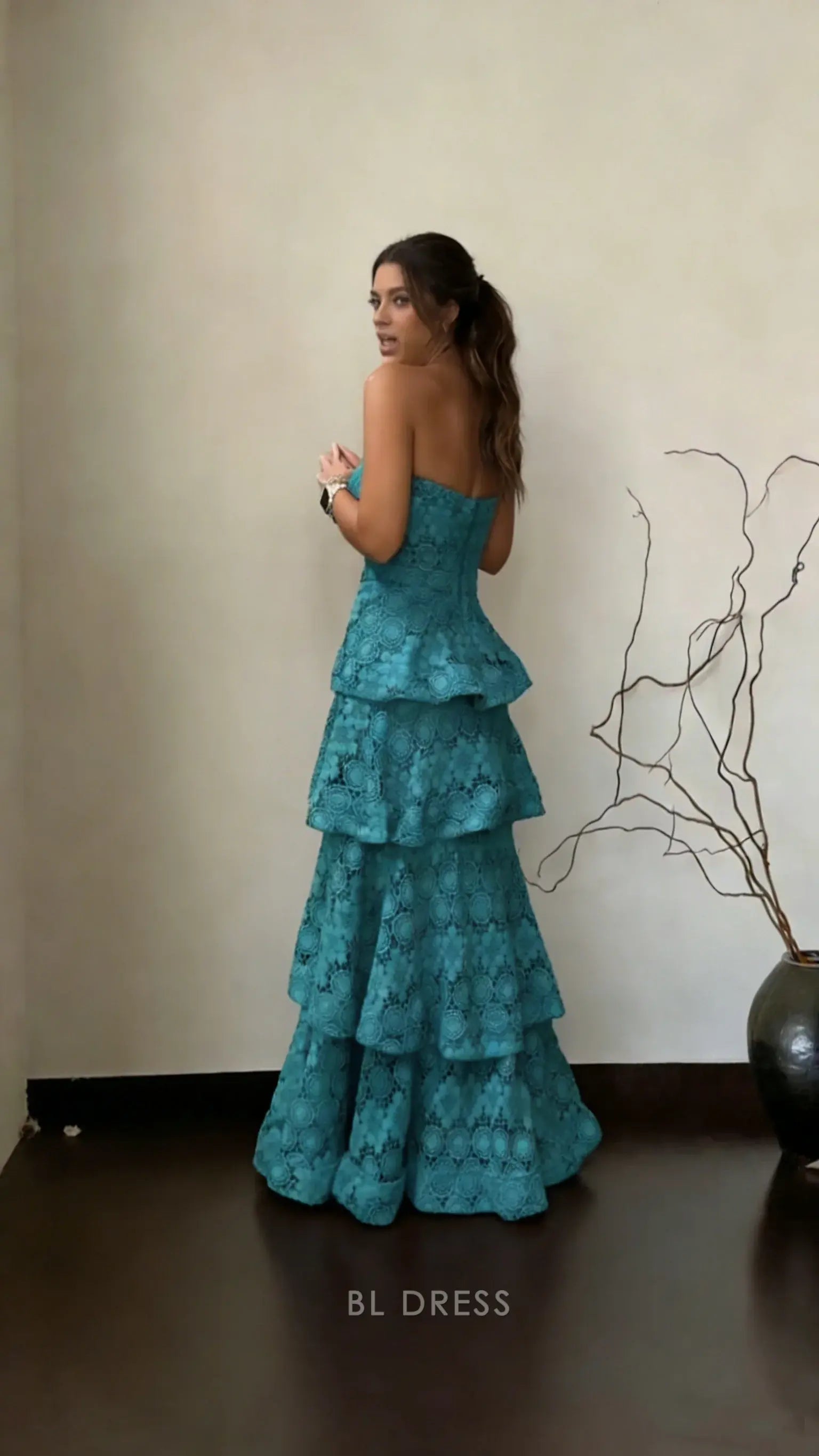Woman walking in flowing teal tiered floral lace prom dress.
