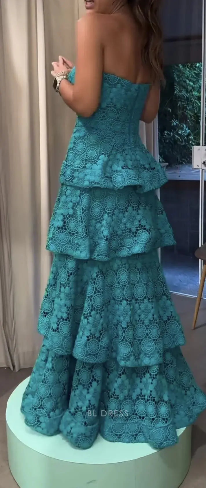 Full length view of woman in teal strapless tiered prom dress.