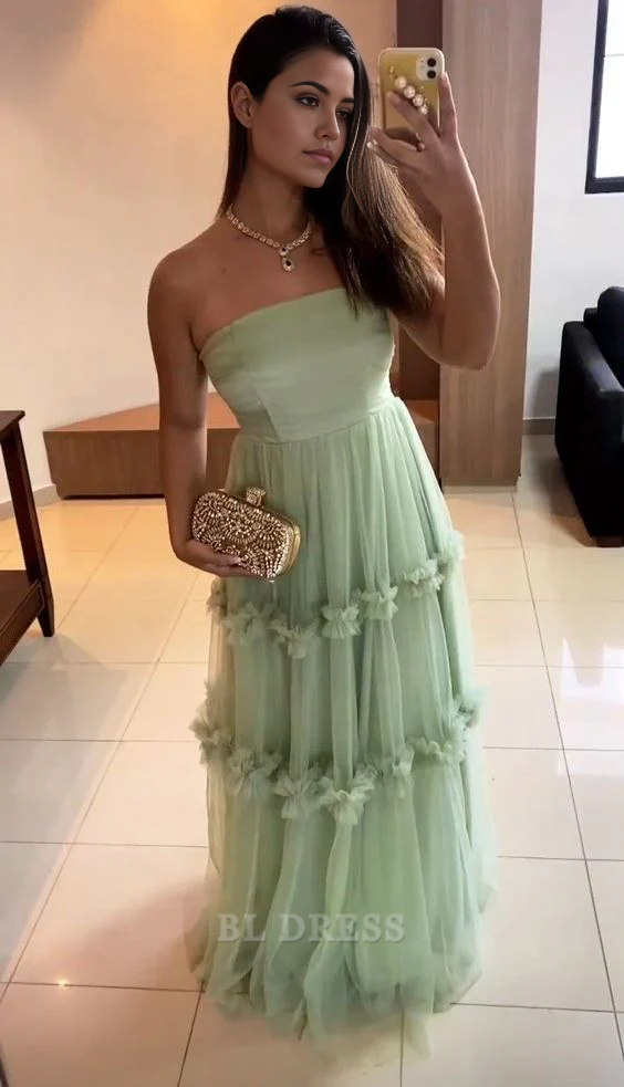 Woman wearing an elegant green A-line strapless tulle formal dress.
