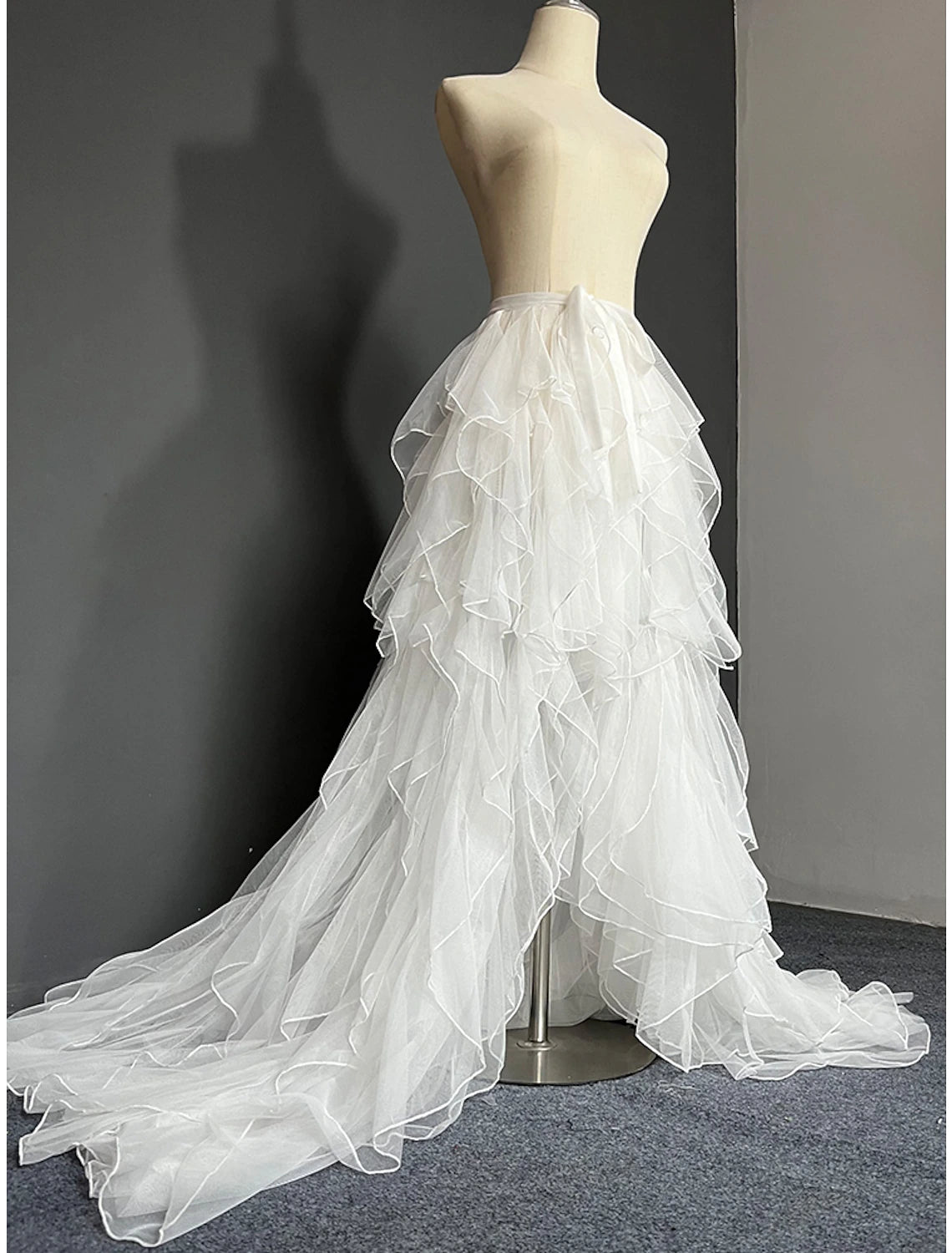 Model wearing an elegant white A-line strapless wedding dress with a detachable tulle overskirt and court train.