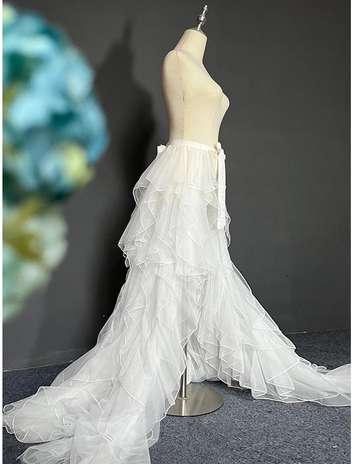 Back view of a model in a white A-line strapless bridal gown featuring a flowing tulle overskirt.