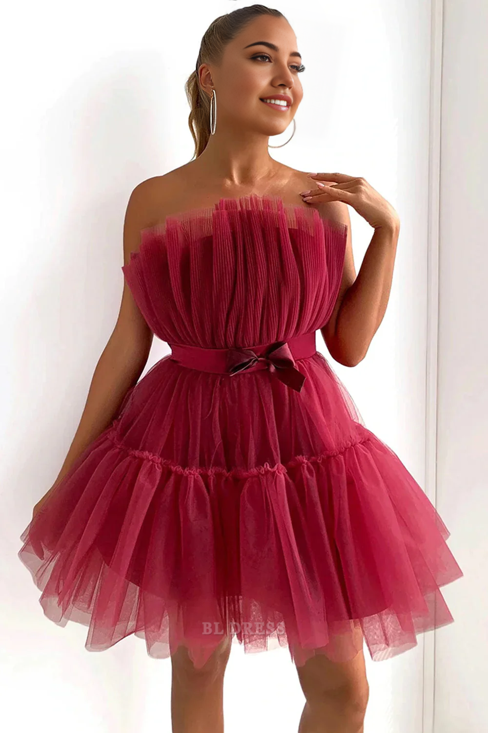 Side view of a model posing in a short tulle formal dress.