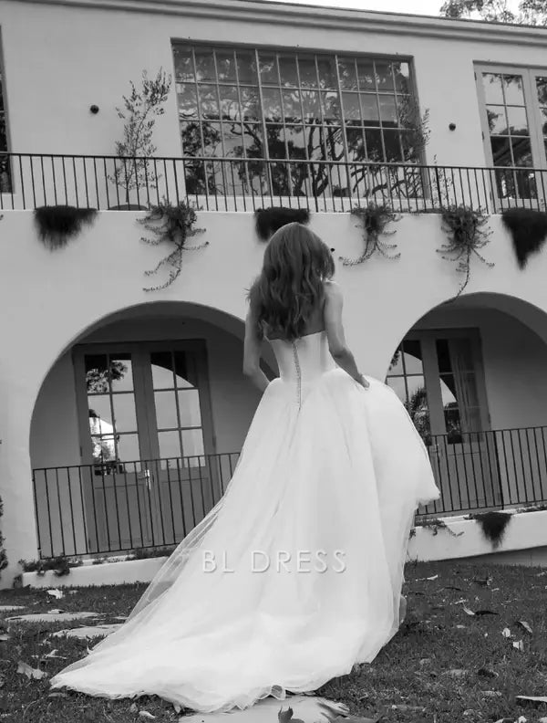 White A-line strapless tulle gown, side view.
