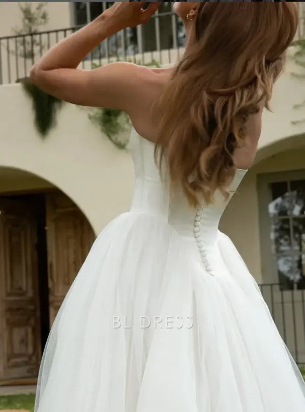 White A-line strapless tulle gown, back view.