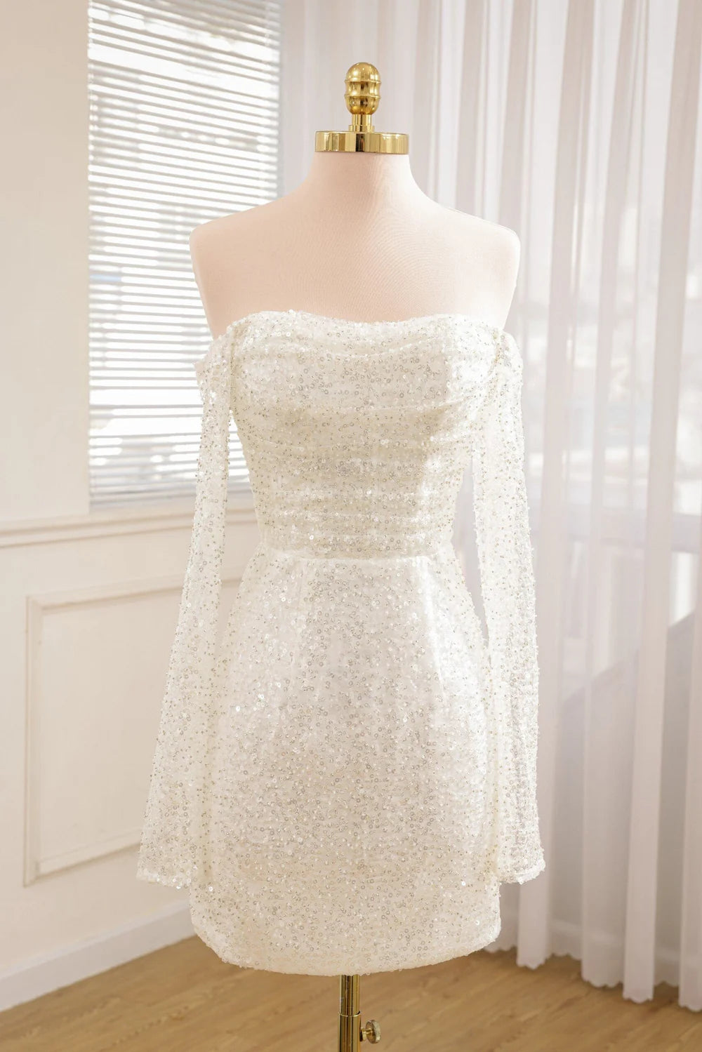 Front view of a short beaded A-line wedding dress with long detachable sleeves.