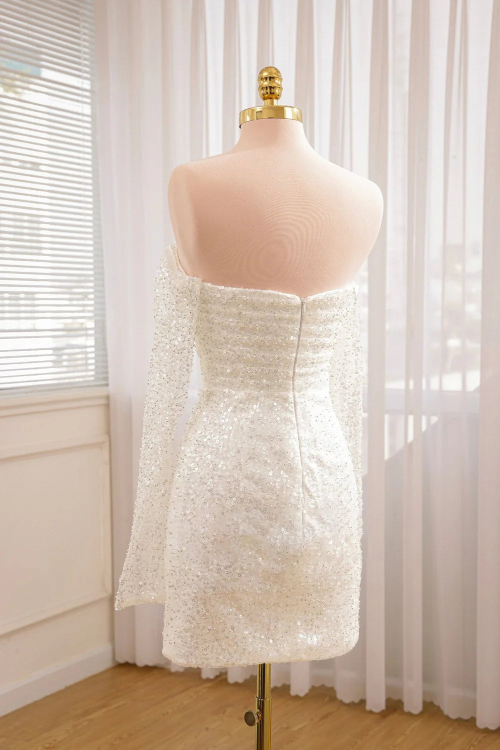 Side profile of a bride wearing a short wedding dress with detachable sleeves.