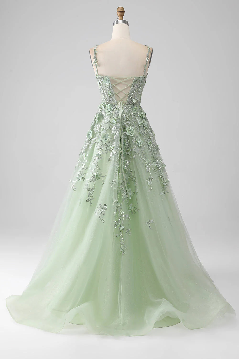 Side view of a sage A-line prom dress, showcasing floral appliques and long silhouette.