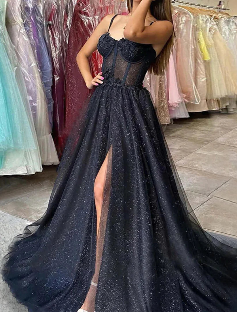 Model posing in a black sweetheart prom dress with a high slit.