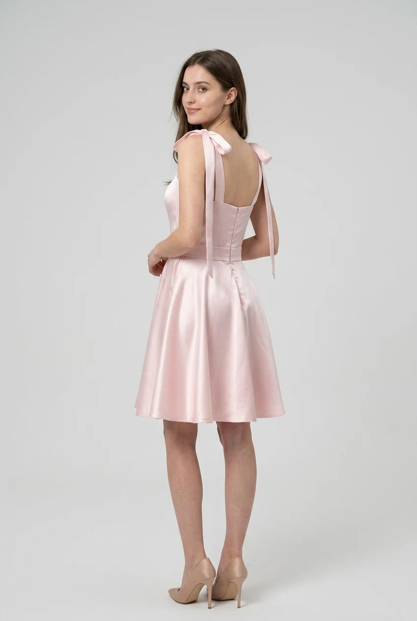 Side view of the ivory satin mini dress, showcasing the flow of the pleated skirt.