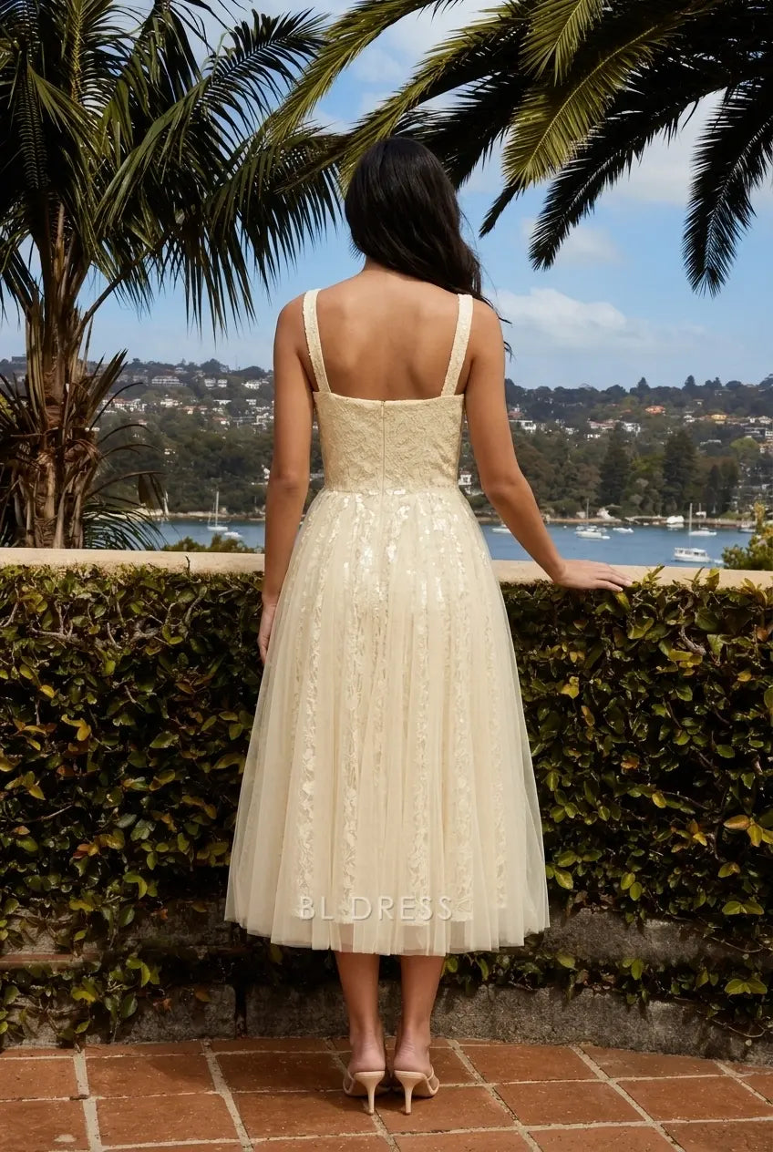 Model in light yellow A-line midi gown, showing layered tulle skirt and lace appliques.