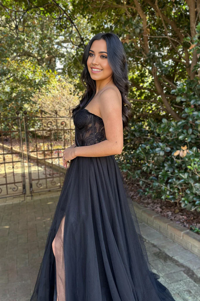 Side profile of a woman wearing a long black lace prom dress.