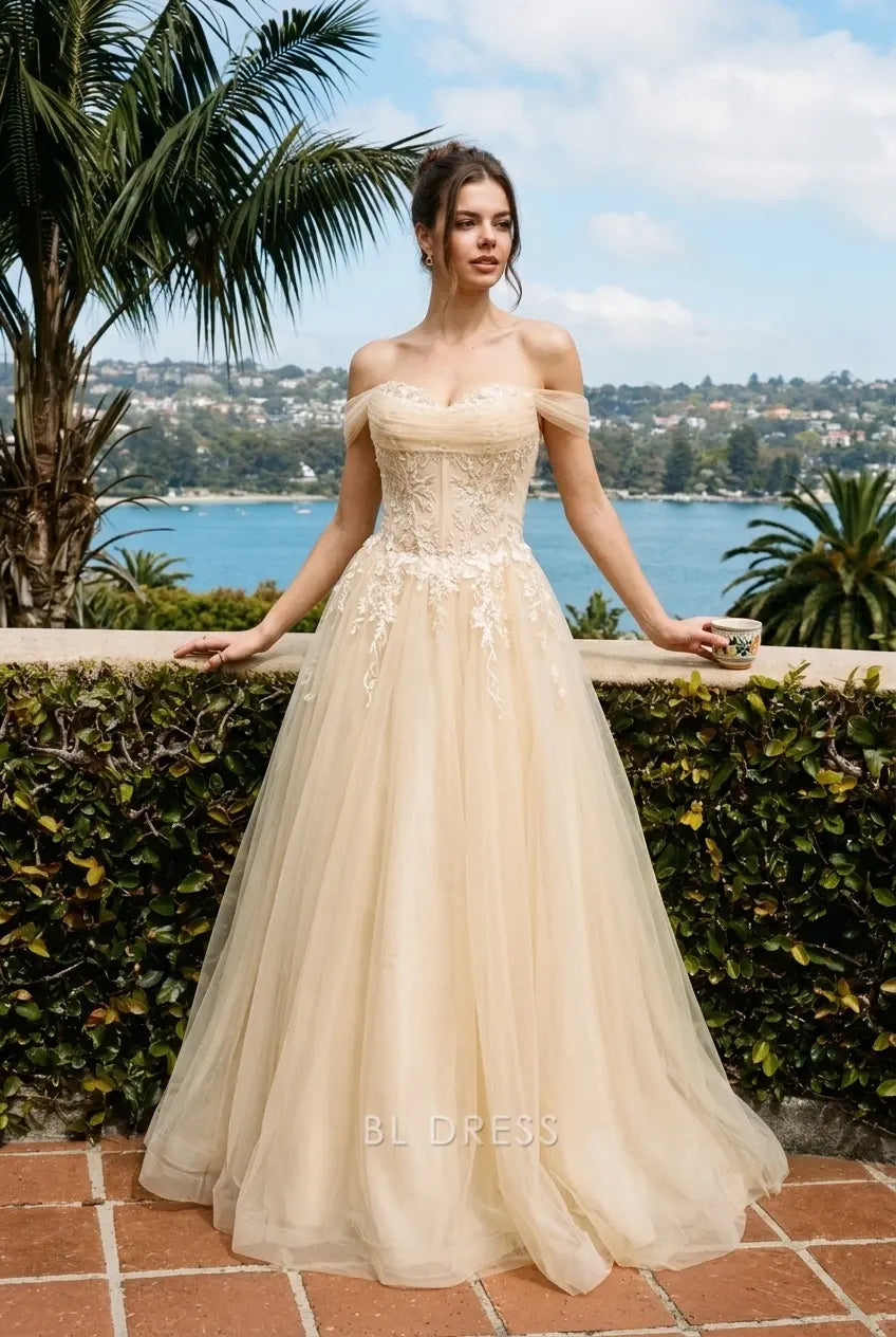 Model posing in champagne A-line gown, highlighting elegant drape and off-shoulder design.