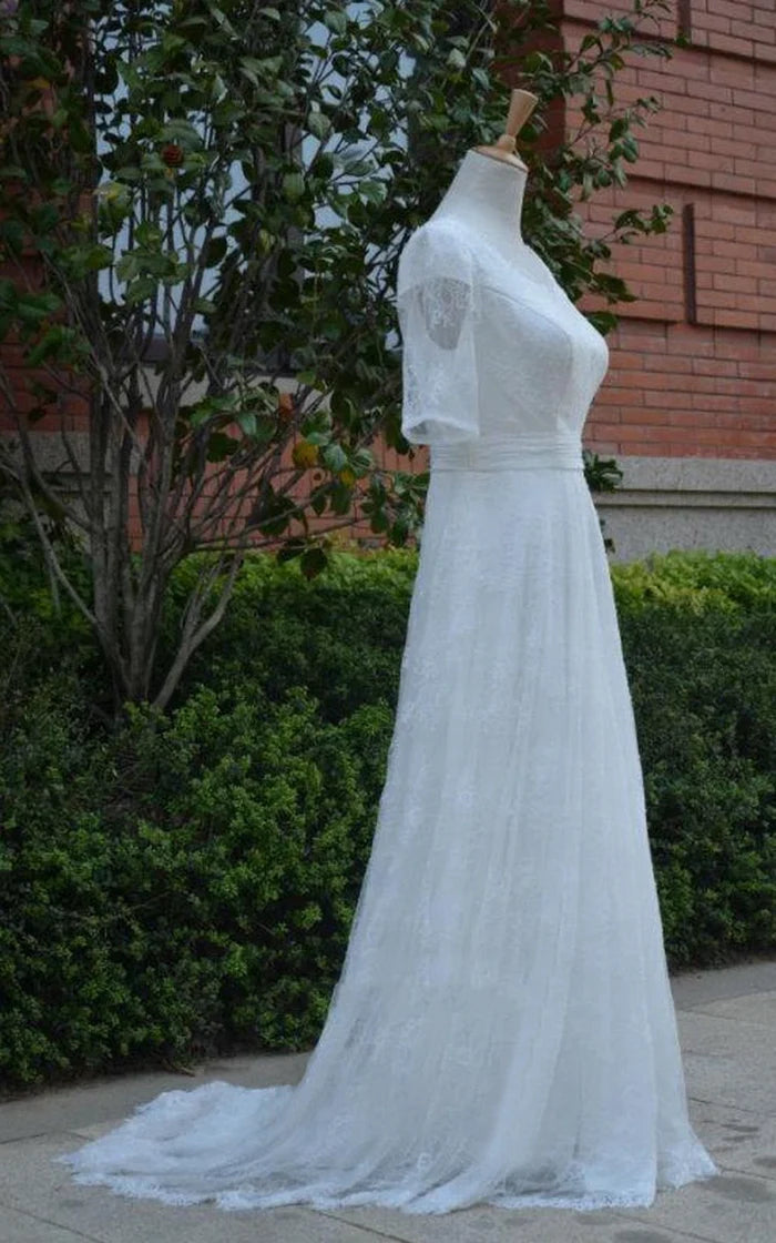 Side profile of a bride wearing a ruched tulle wedding dress with sweetheart neckline and illusion sleeves.