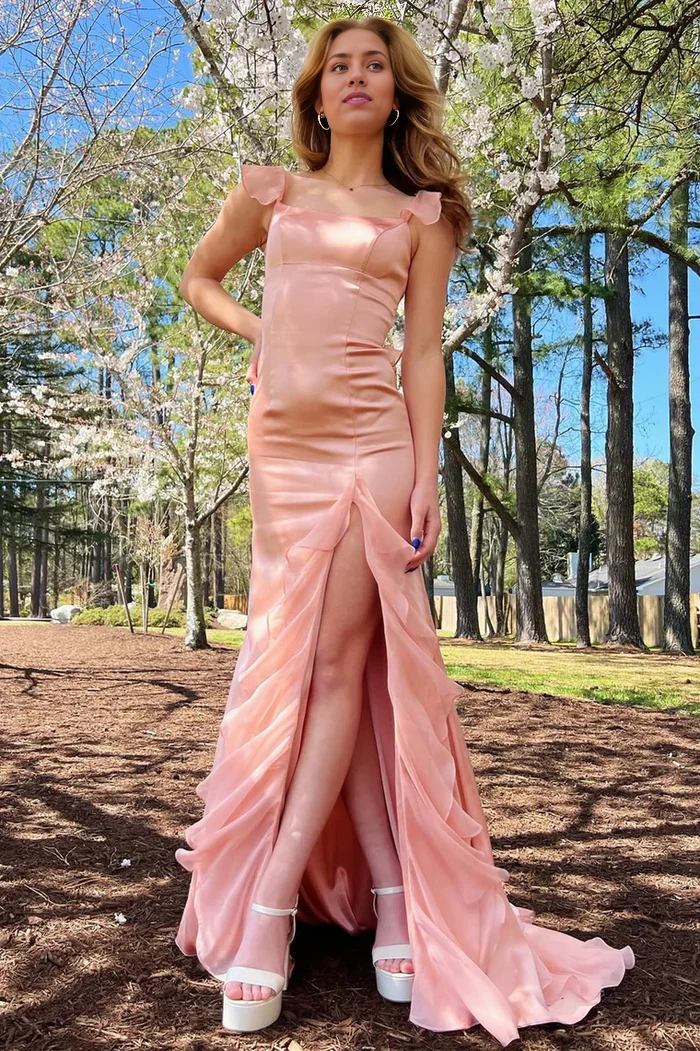 Woman posing in a sweetheart A-line prom dress with ruffle and slit.