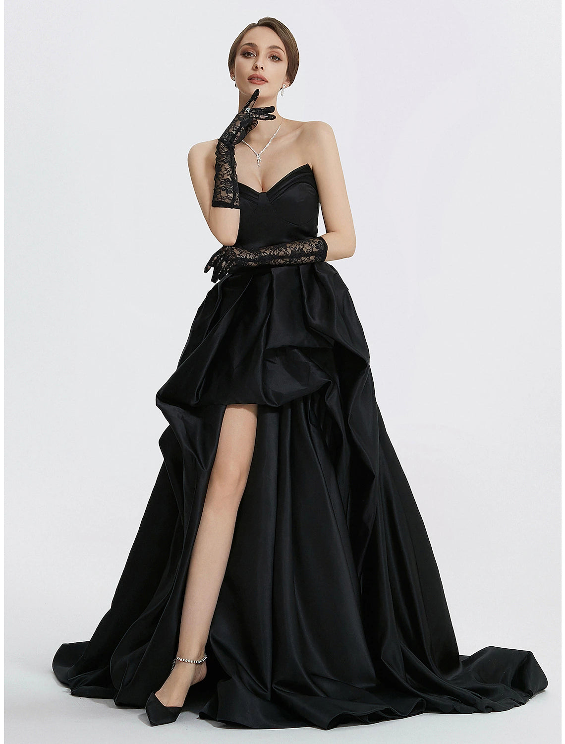 Woman wearing a navy blue A-line sweetheart satin evening gown with a ruched slit and sweep train.