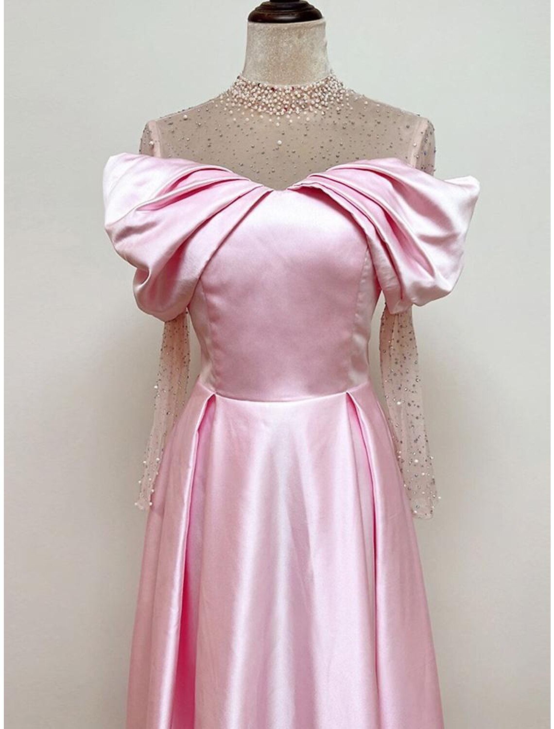 Close-up of sweetheart neckline on satin gown with pearl and crystal embellishments.