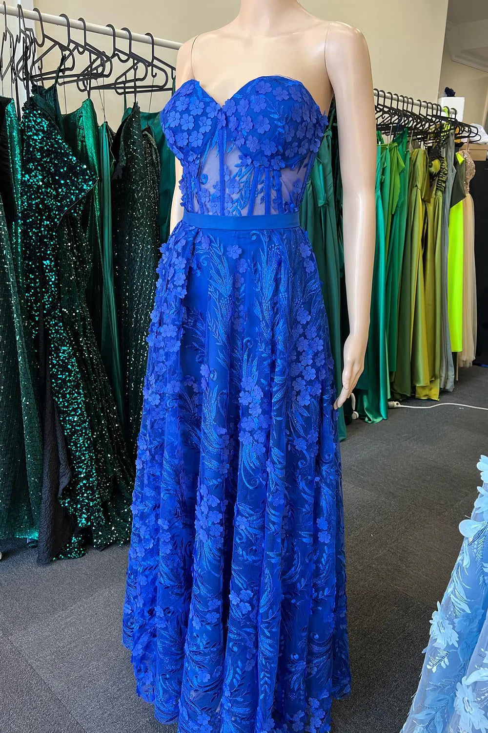 Front view of a royal blue long prom dress with appliques and a sweetheart corset.