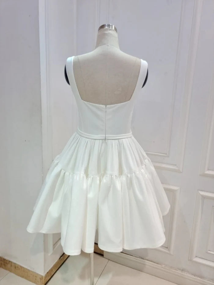 Model wearing a sleeveless A-line mini bridal dress, side view.